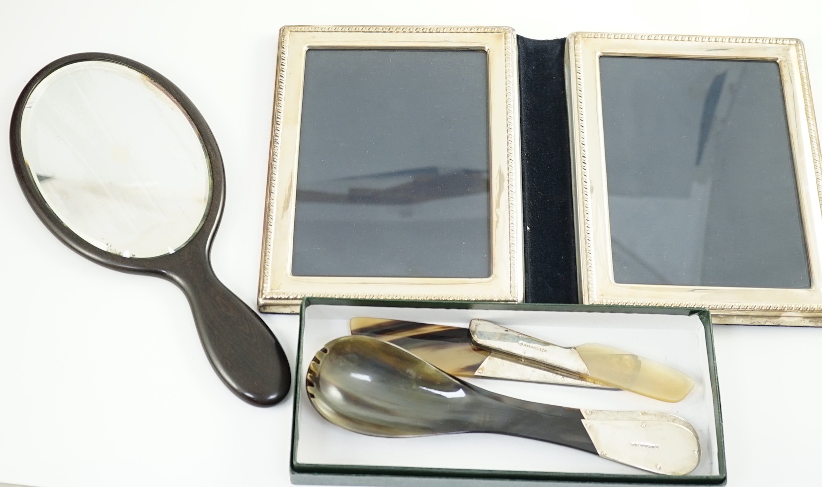 A silver mounted double photograph frame, 23 cm. a pair of silver mounted horn salad servers and two matching knives and an ebony dressing table set.